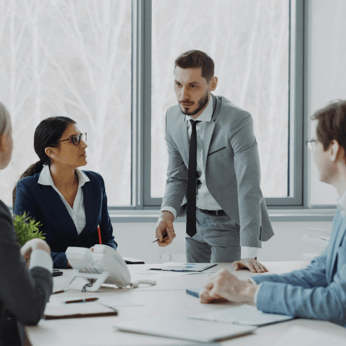 Senior energy executives in a modern meeting room discussing renewable energy projects, oil and gas operations, and infrastructure strategy with digital dashboards in the background